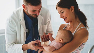 Male doctor with mom and young baby for health check-up.
