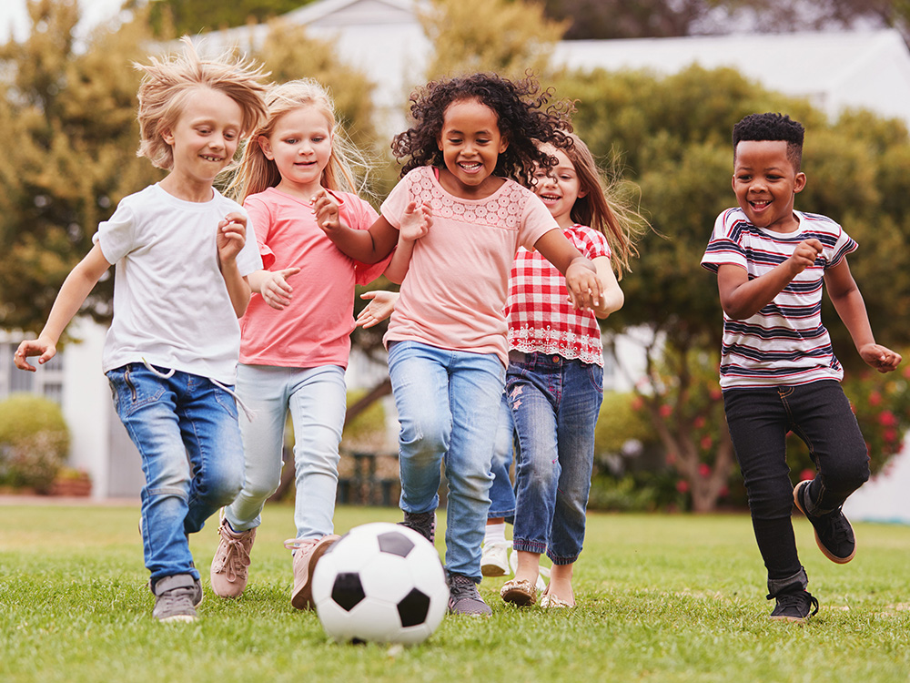 Young kids playing soccer outside.