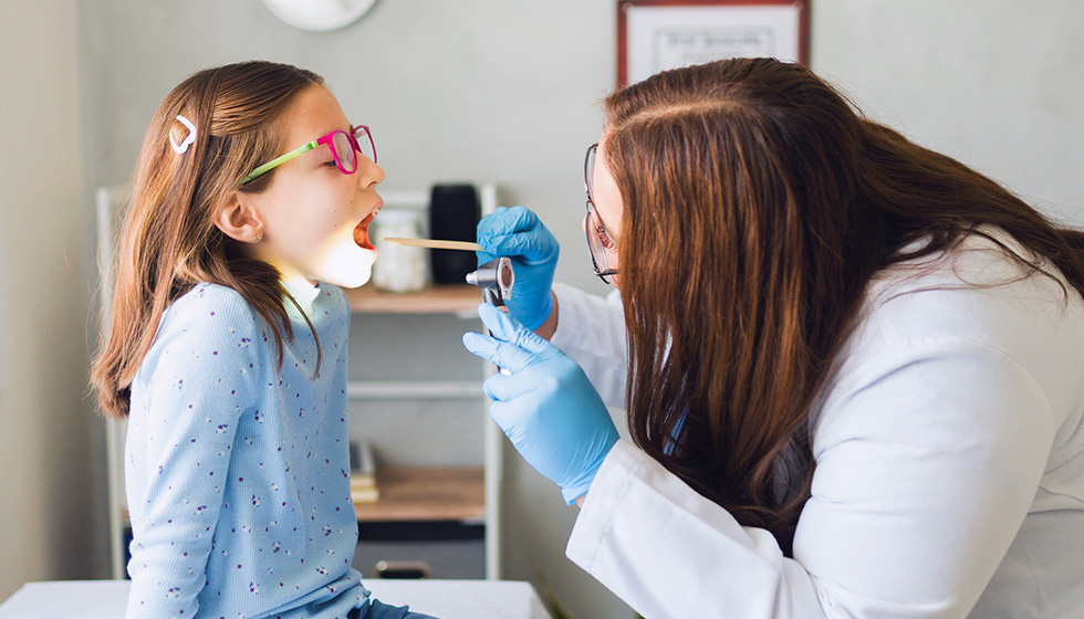 Doctor examining throat of young girl