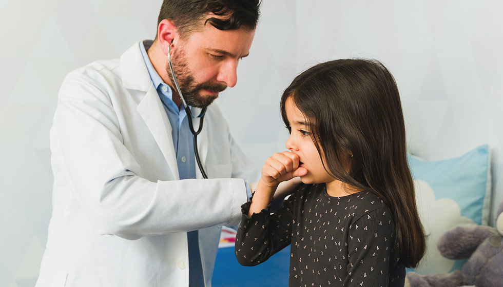 Doctor using stethoscope to listen to cough of young girl